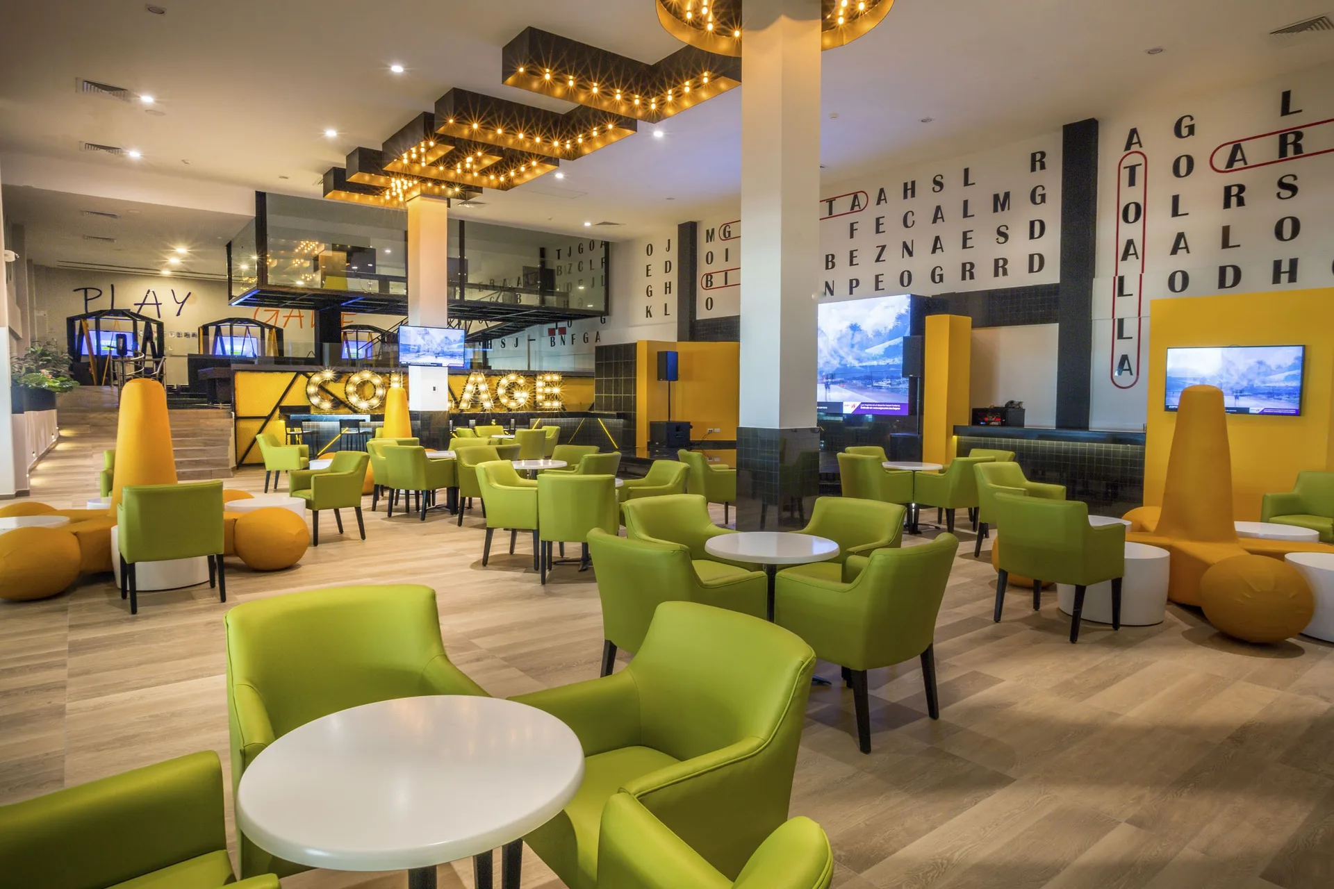 Game lounge with lime chairs and screens at Sensira Resort & Spa Riviera Maya.