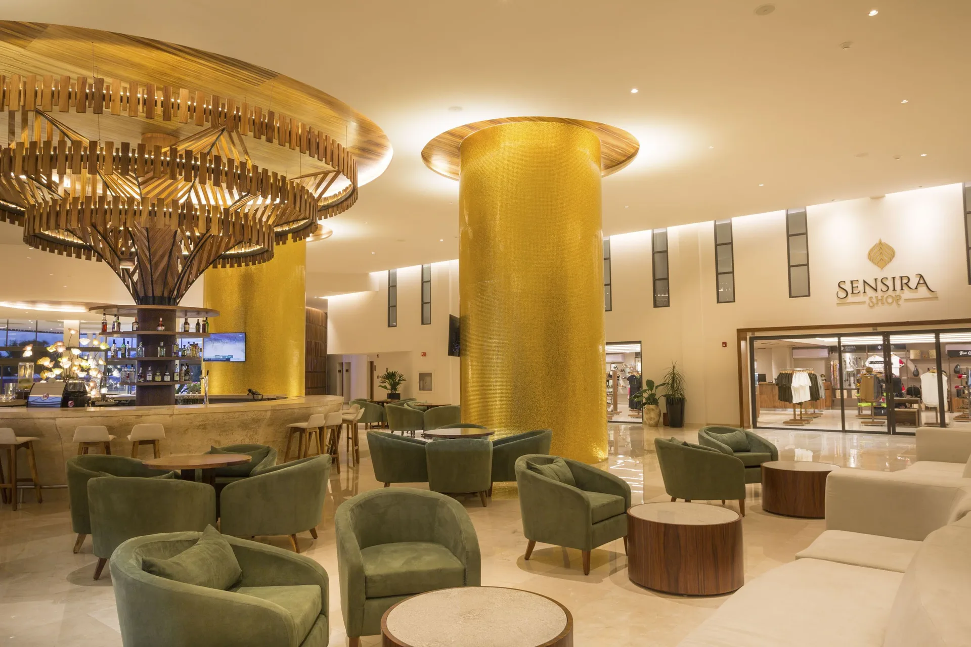 Lobby lounge with gold columns and bar at Sensira Resort & Spa Riviera Maya.