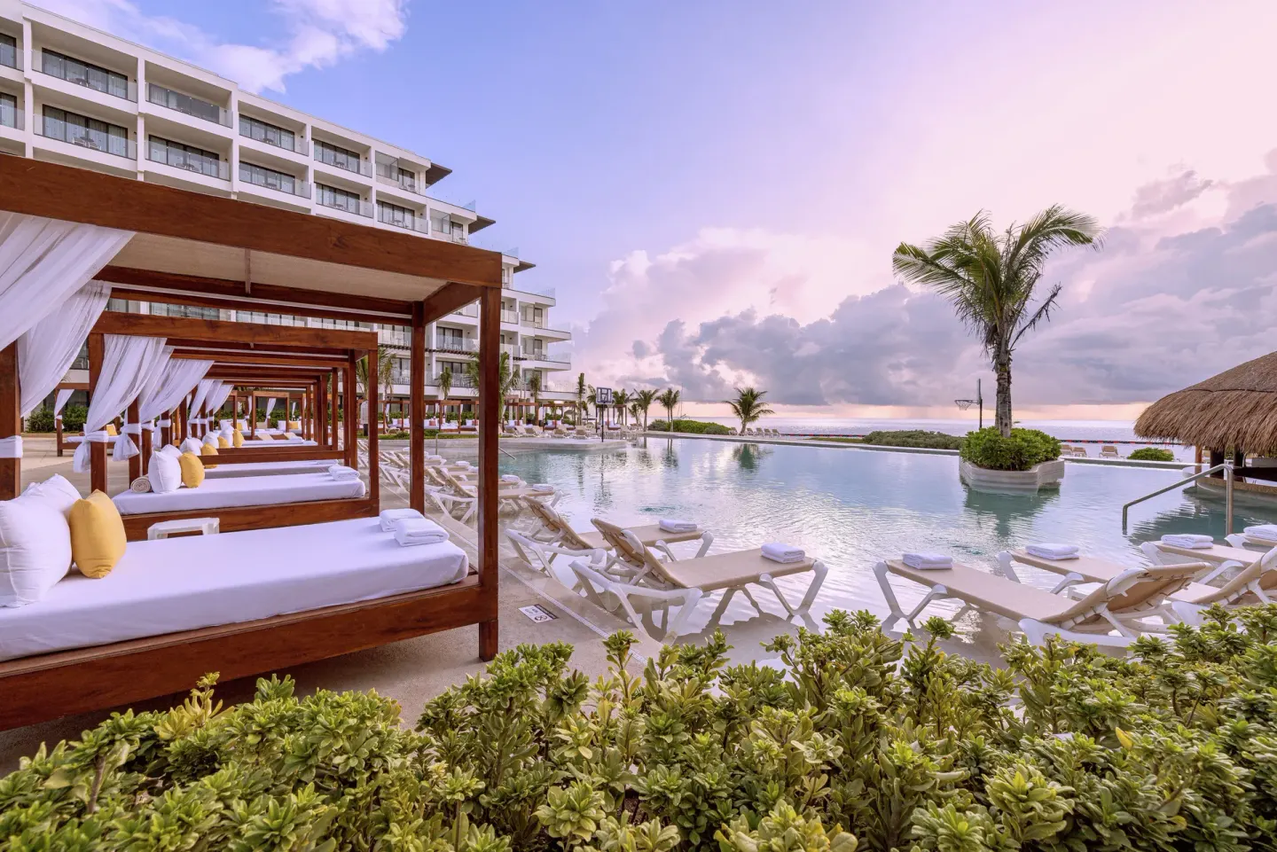 Poolside cabanas and loungers beside the ocean at Sensira Resort & Spa Riviera Maya.