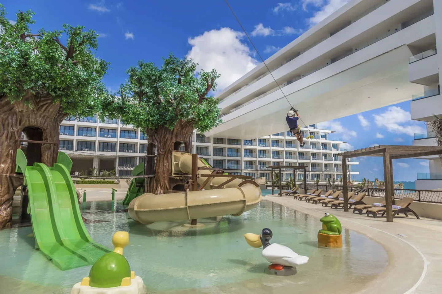 Splash pool with tree slides and a zip line overhead at Sensira Resort & Spa Riviera Maya.