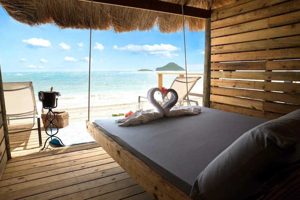 Thatched beach cabana daybed facing ocean at Serenity At Coconut Bay