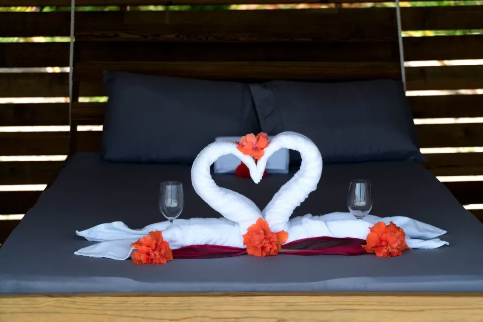 King bed with towel swans and floral accents at Serenity At Coconut Bay