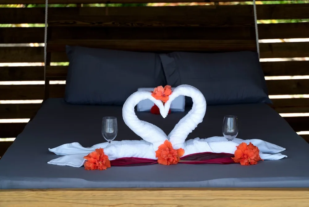 Romantic daybed with towel swans and flowers at Serenity At Coconut Bay