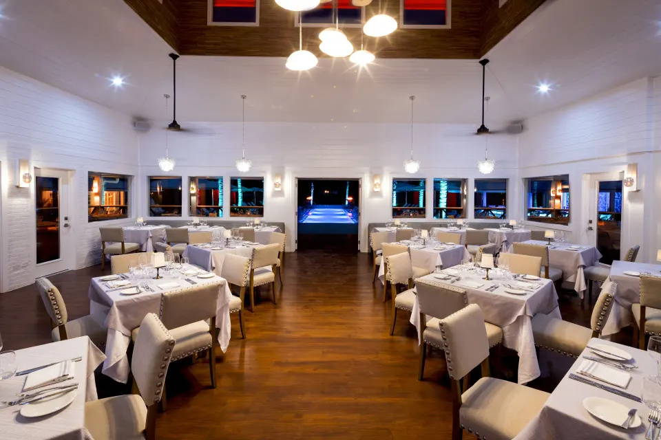 Dining room with neatly set tables and wooden floor at Serenity At Coconut Bay.