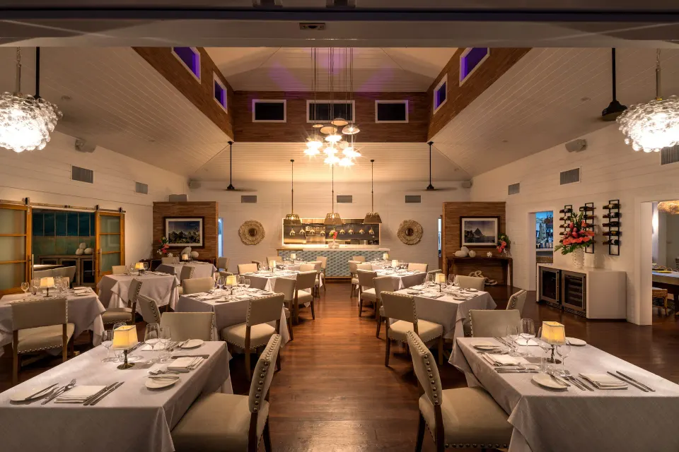 Warmly lit restaurant interior with tables set for dinner at Serenity At Coconut Bay.