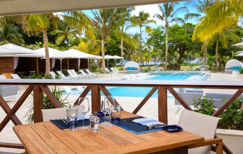Poolside dining table set with glassware and cutlery overlooking resort pool at Serenity At Coconut Bay