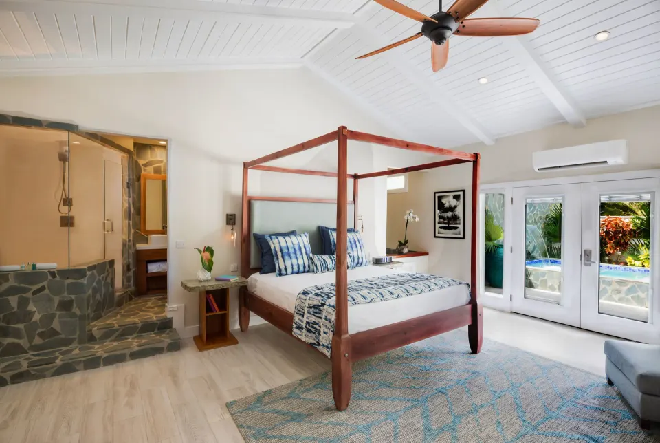 King bed and sitting area with glass doors opening to a pool at Serenity At Coconut Bay