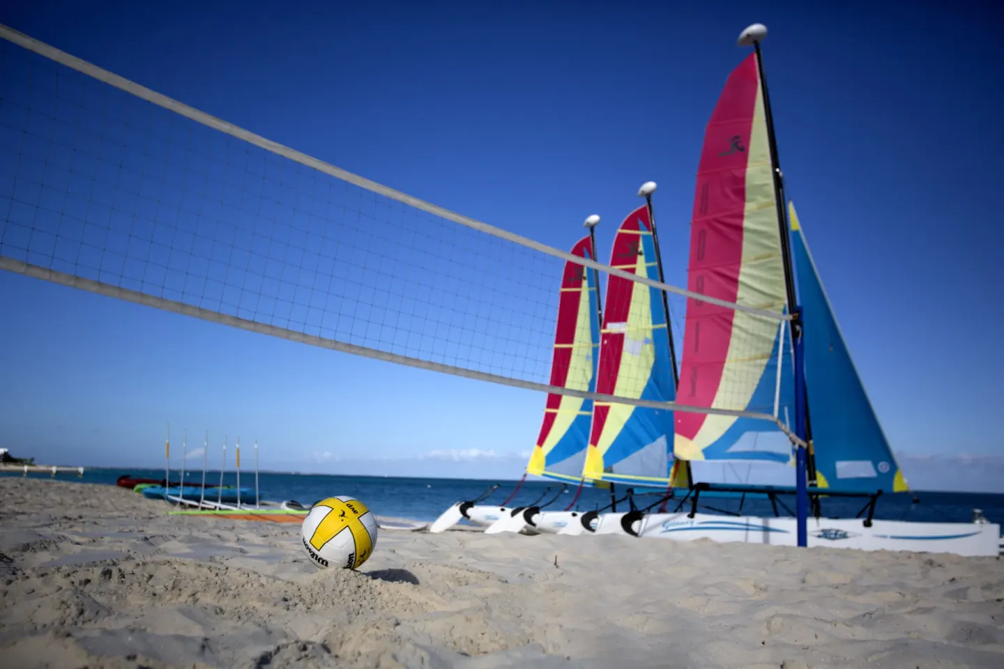 Beach volleyball net and colorful sailboats on the sand at Seven Stars Resort & Spa.
