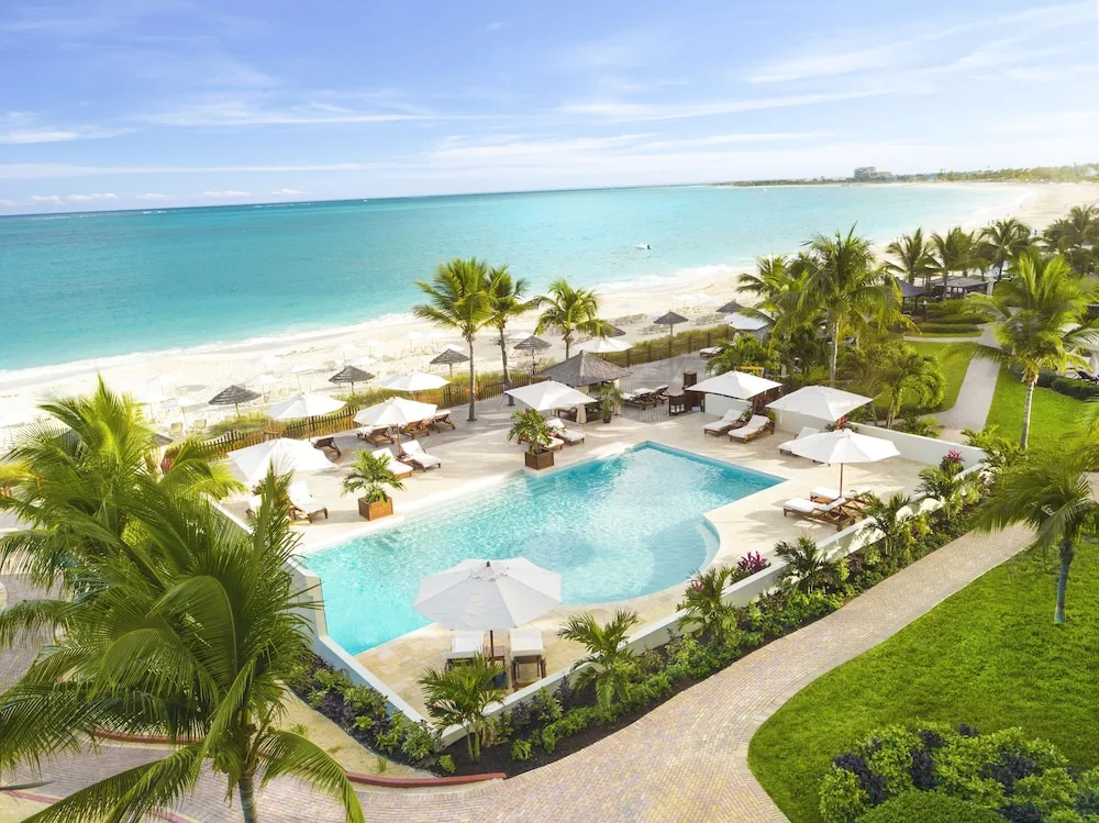 Elevated view of beachfront pool, umbrellas, lawn, and ocean at Seven Stars Resort & Spa.
