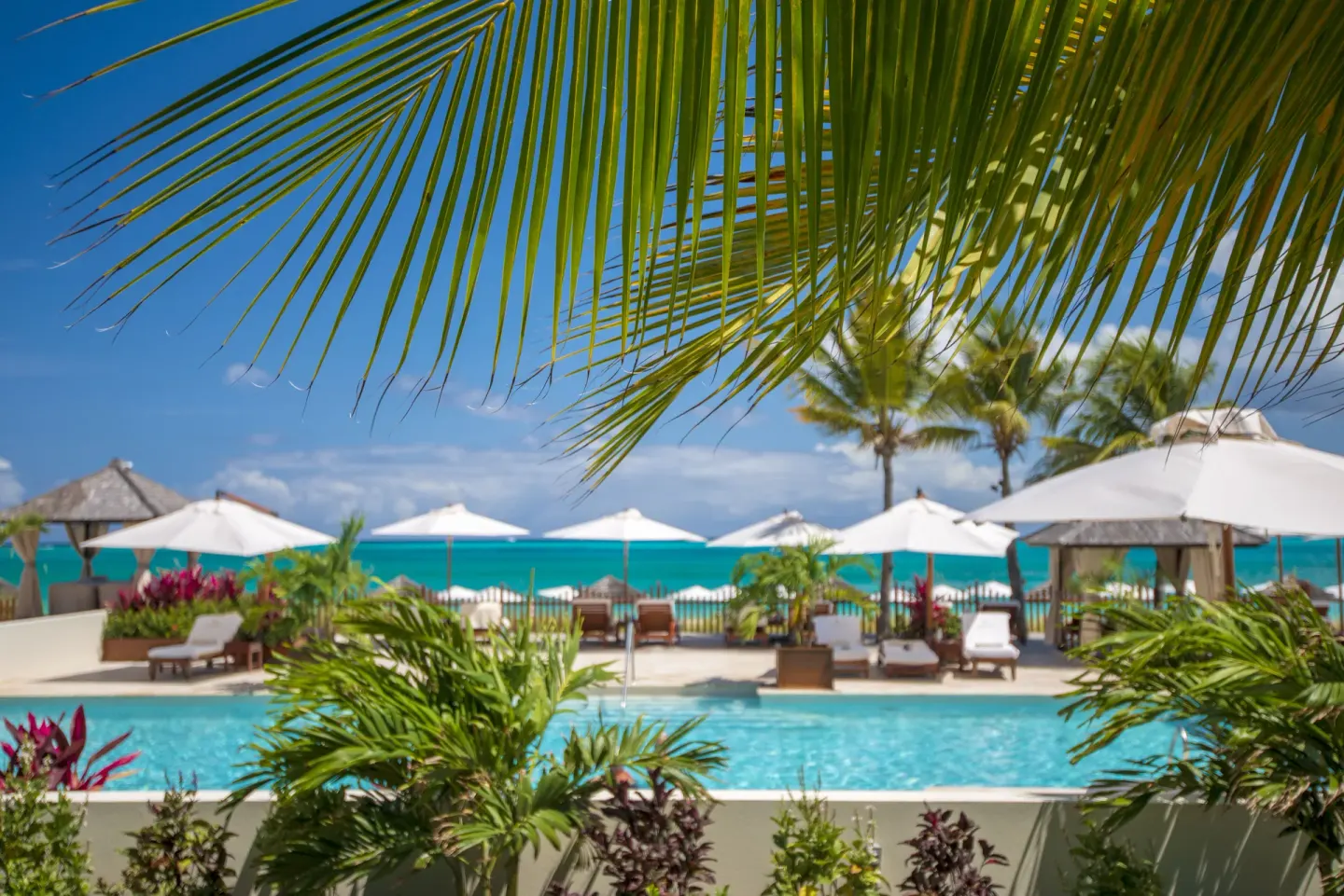 Pool, palms, umbrellas, and turquoise sea at Seven Stars Resort & Spa.
