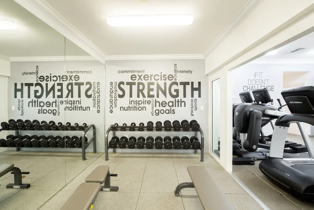 Fitness room with dumbbells, benches, mirrors, and cardio machines at Seven Stars Resort & Spa.