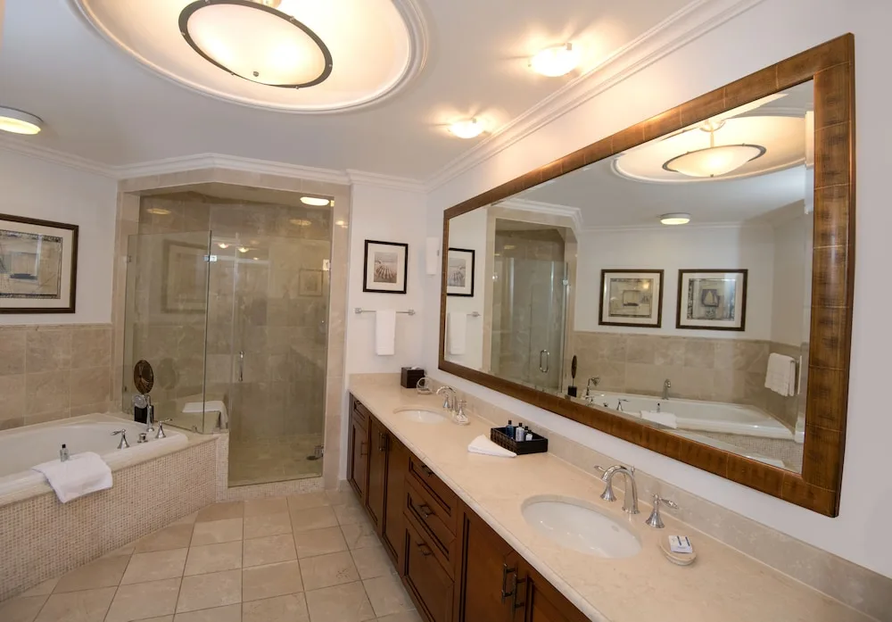 Guest bathroom with large mirror, tub, and glass shower at Seven Stars Resort & Spa.