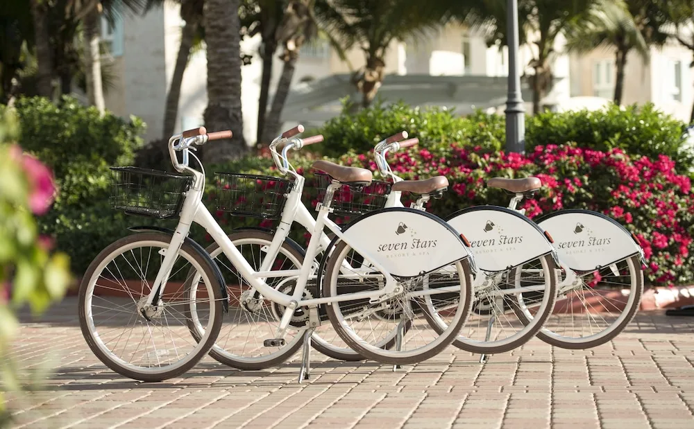 White guest bicycles lined up by flowers and palms at Seven Stars Resort & Spa.