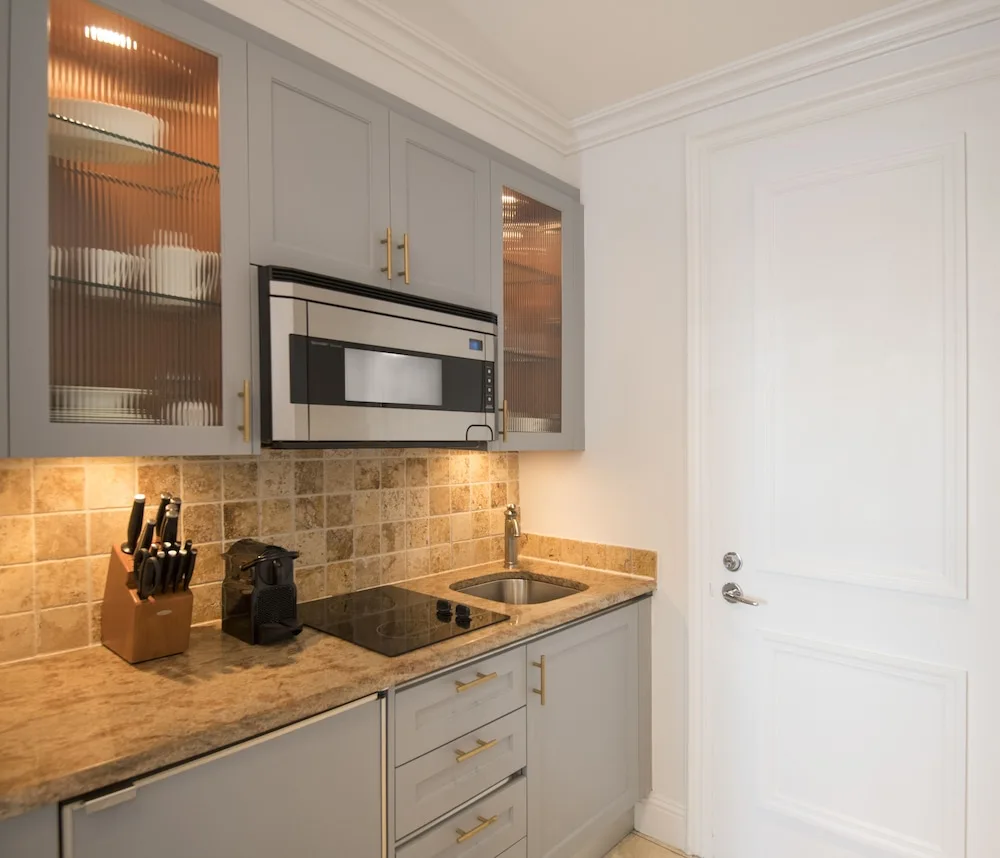 Compact kitchenette with cabinets, microwave, cooktop, and sink at Seven Stars Resort & Spa.
