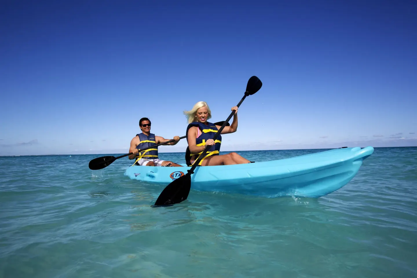 Two guests kayaking on turquoise water near Seven Stars Resort & Spa.