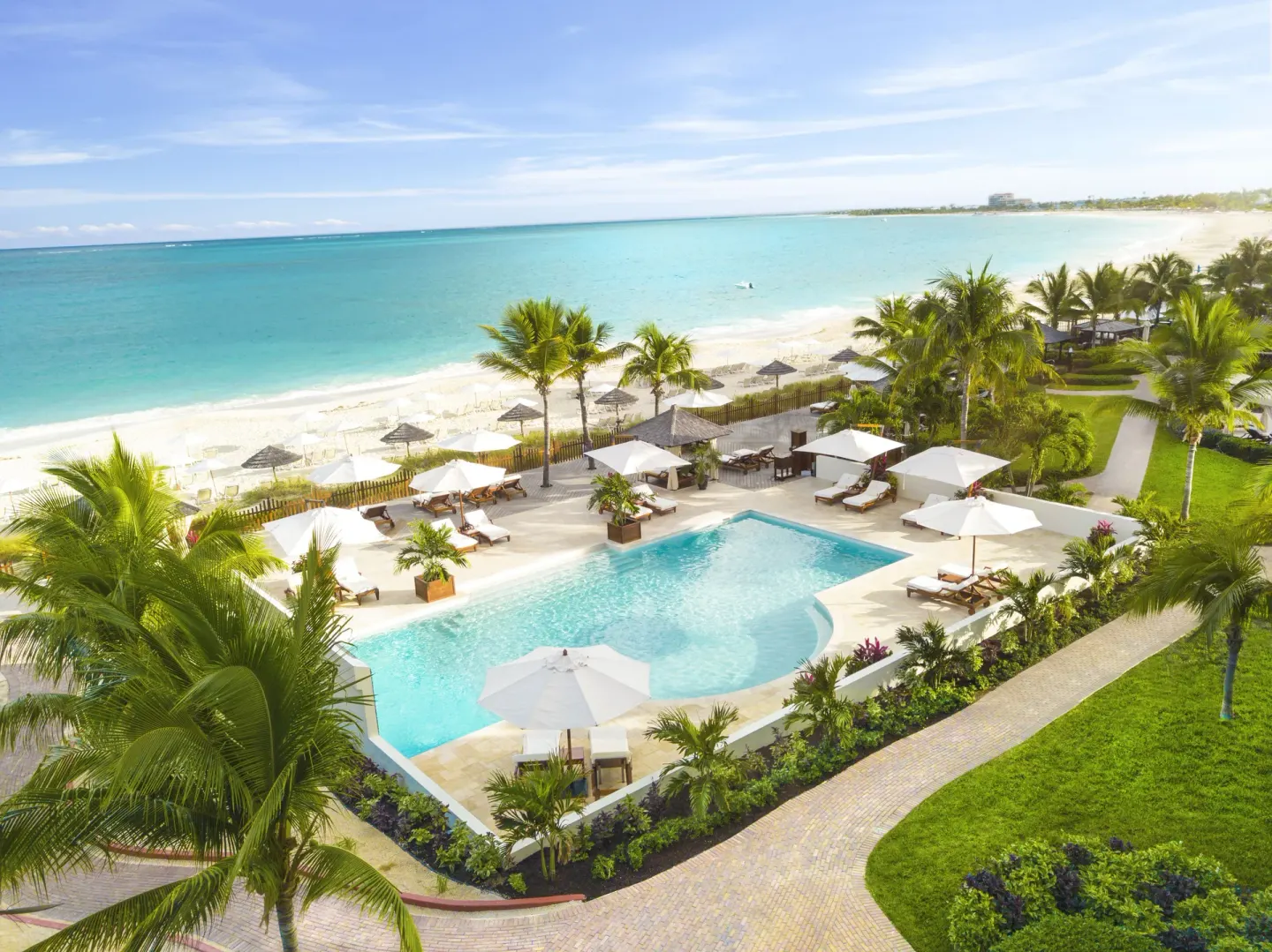 Pool terrace with umbrellas, palms, and beach beyond at Seven Stars Resort & Spa.