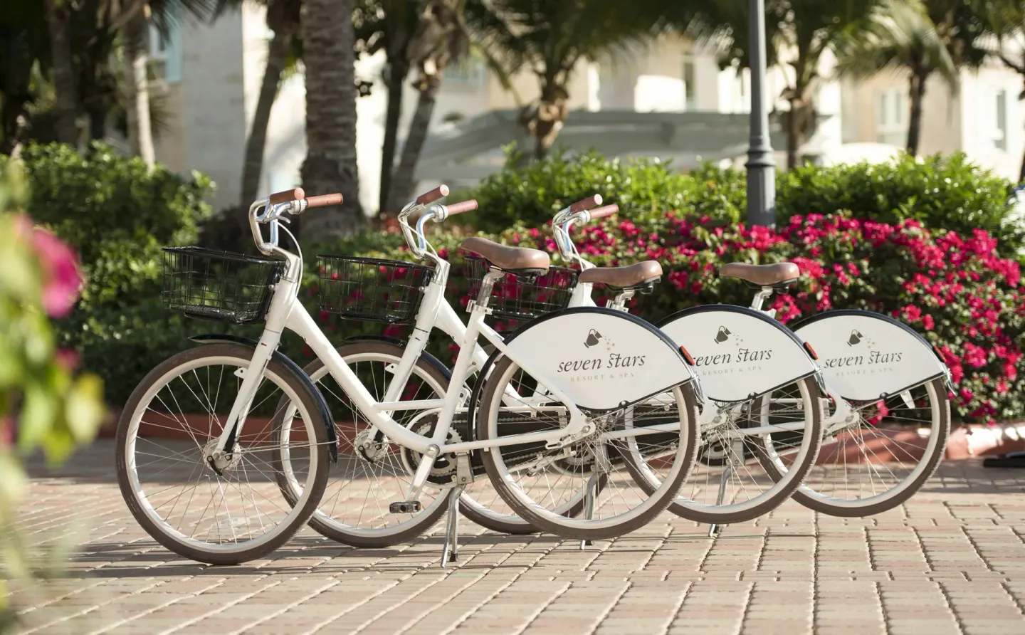 White resort bicycles lined up in gardens at Seven Stars Resort & Spa.