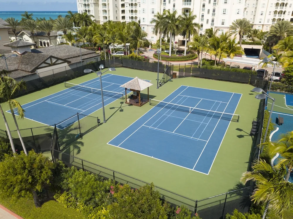 Two blue tennis courts bordered by palms and resort buildings at Seven Stars Resort & Spa.