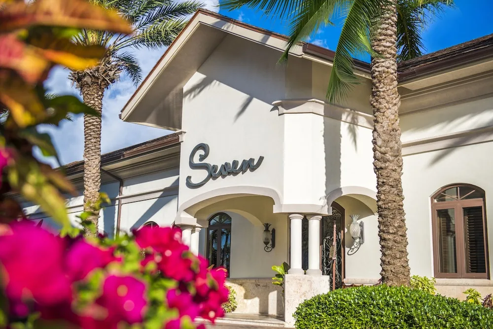Exterior entrance with Seven sign, palms, and bright flowers at Seven Stars Resort & Spa.