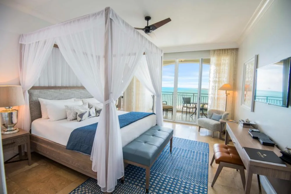 Junior Oceanfront Suite bedroom with canopy bed and balcony at Seven Stars Resort & Spa.
