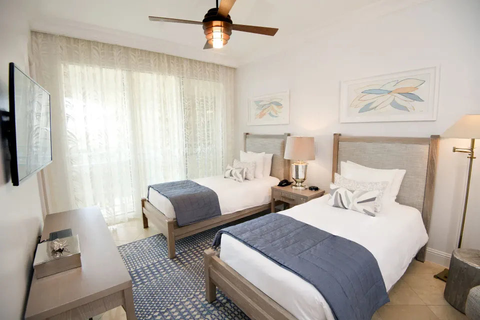 Two twin beds in a two-bedroom island view suite at Seven Stars Resort & Spa beside a large curtained window.
