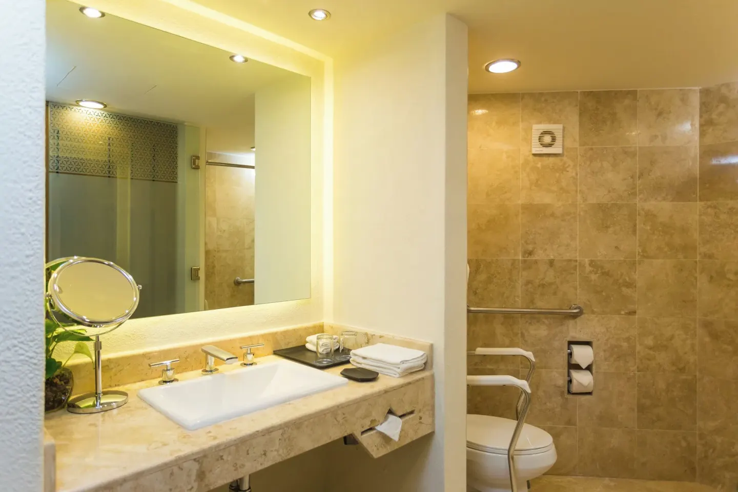 Bathroom vanity and toilet area with stone tile at Sheraton Buganvilias Puerto Vallarta.