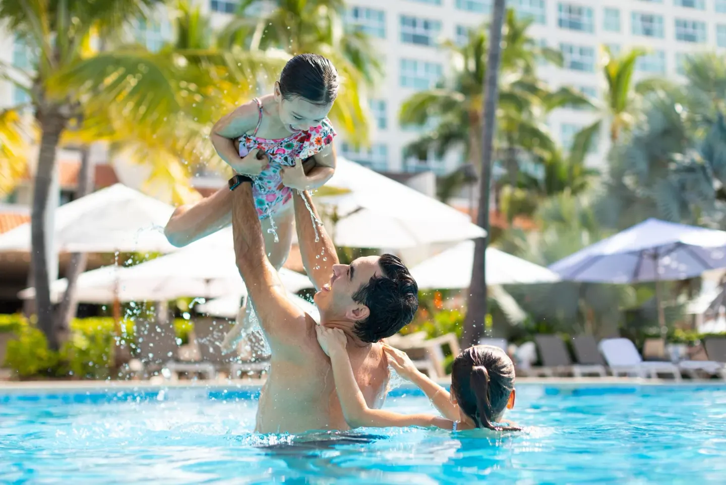 Family playing together in the resort pool at Sheraton Buganvilias Puerto Vallarta.
