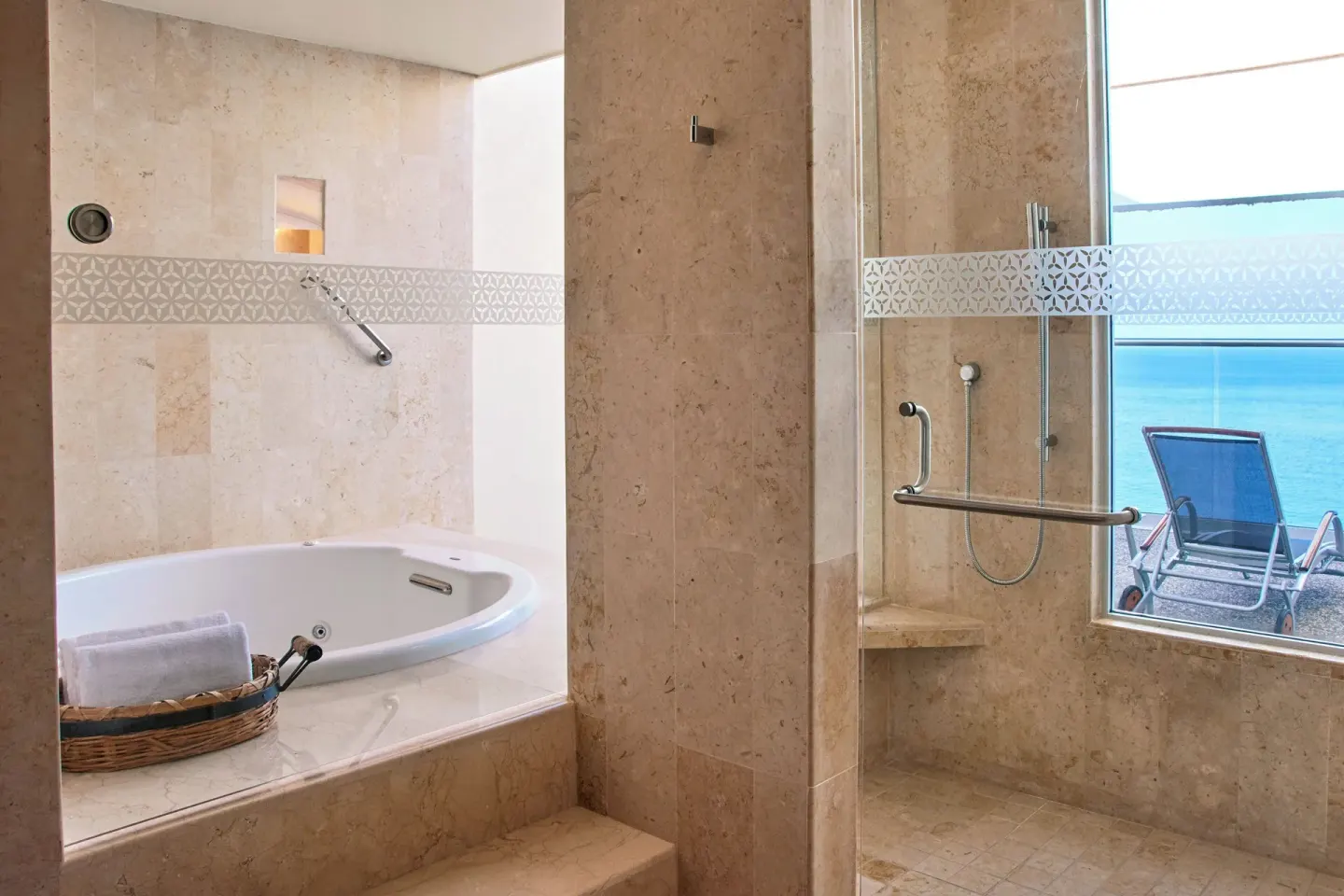 Marble bathroom with tub, shower, and ocean-facing window at Sheraton Buganvilias Puerto Vallarta.