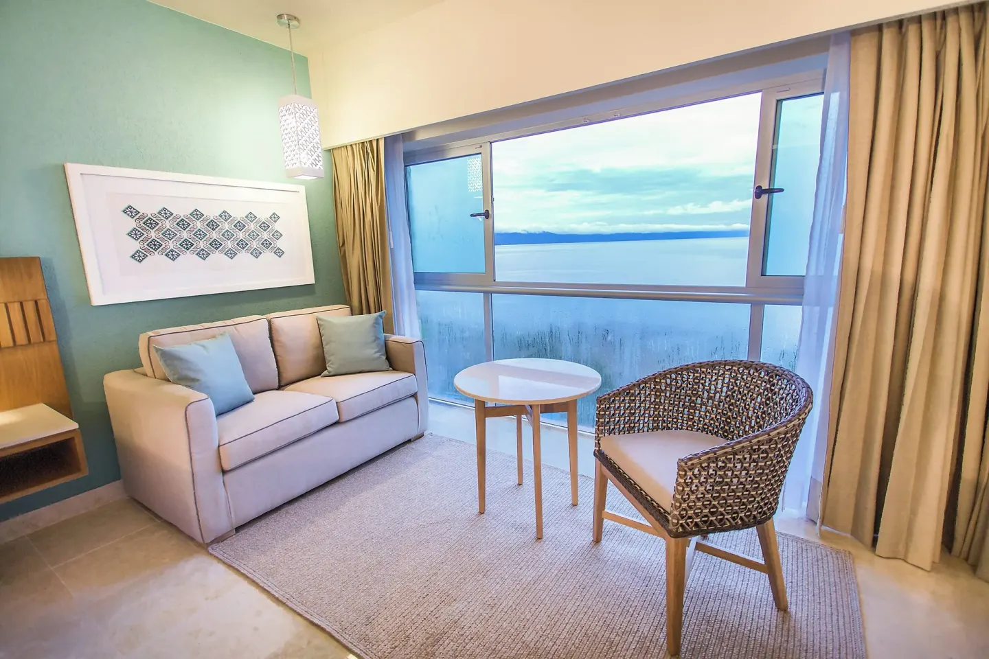 Ocean view sitting nook with sofa and woven chair at Sheraton Buganvilias Puerto Vallarta.