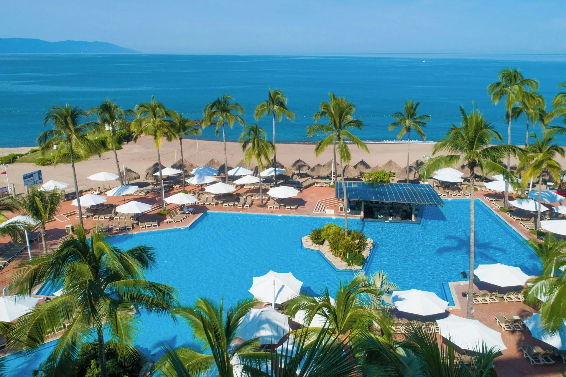 Oceanfront pool and palm-lined beach at Sheraton Buganvilias Puerto Vallarta.