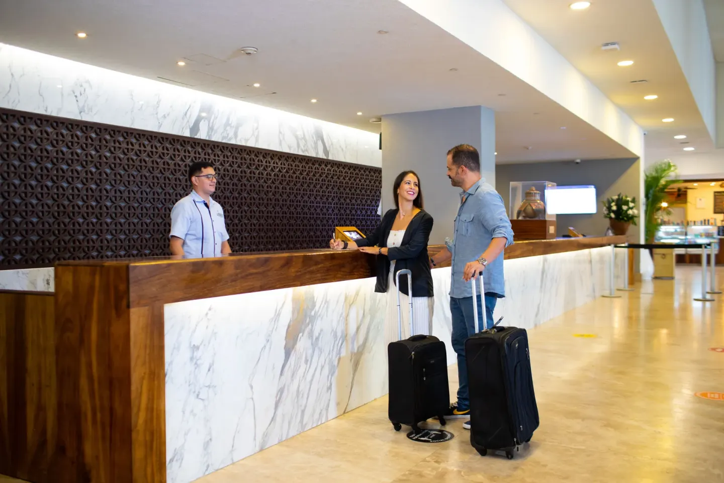 Smiling guests with luggage at the reception desk of Sheraton Buganvilias Puerto Vallarta.