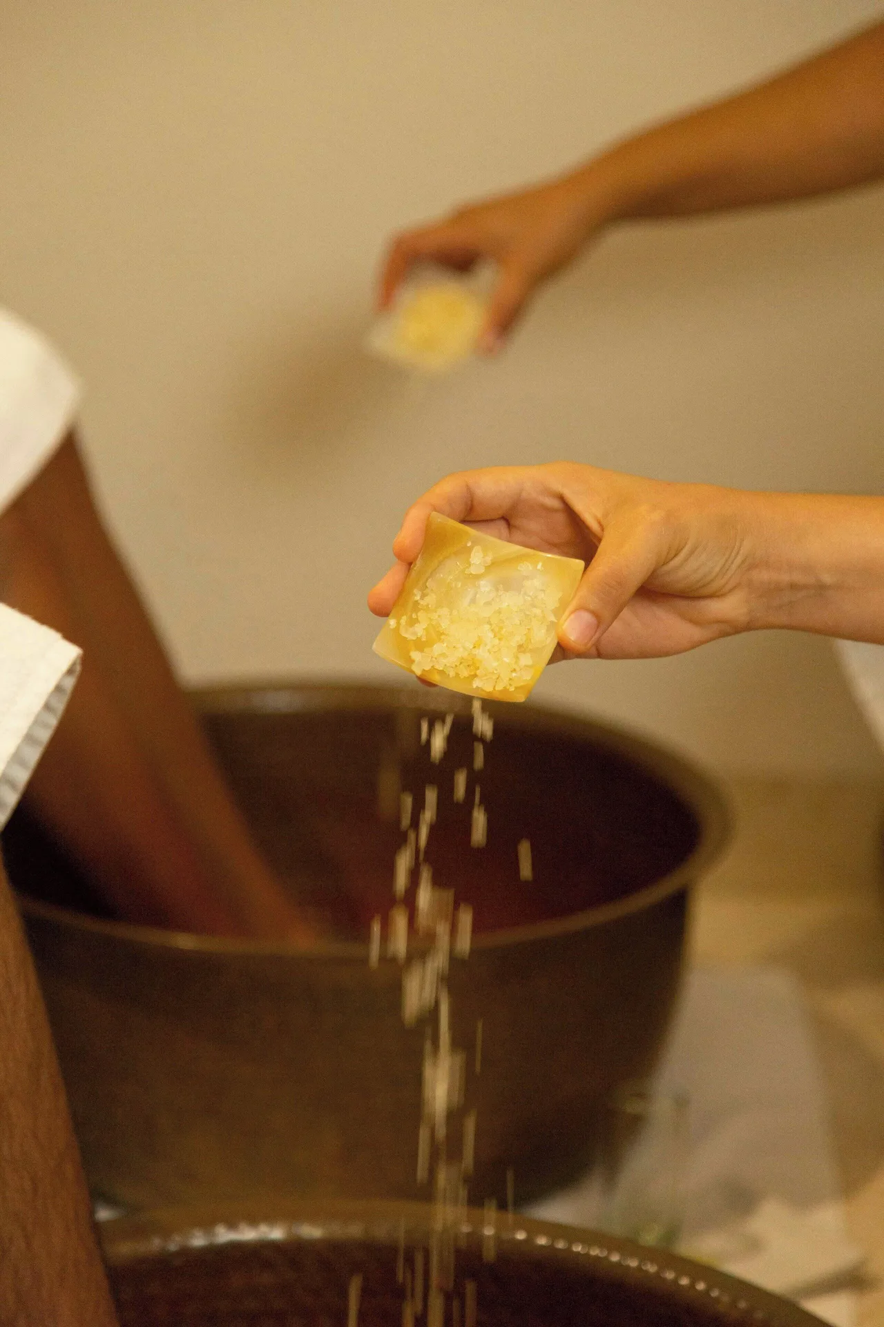 Hands sprinkle bath salts over a foot soak at Sheraton Buganvilias Puerto Vallarta.