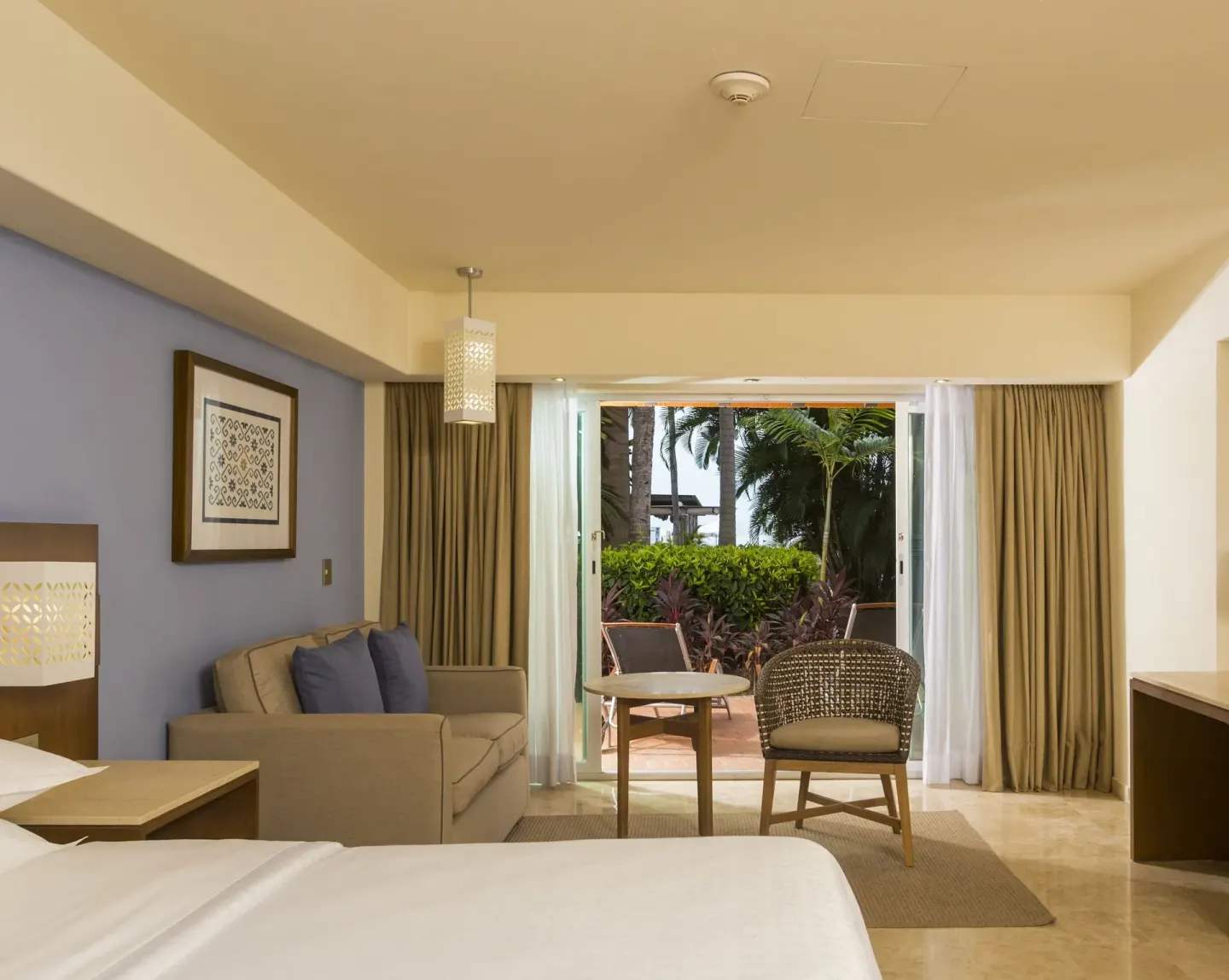 Deluxe Garden View room bed and patio at Sheraton Buganvilias Puerto Vallarta.