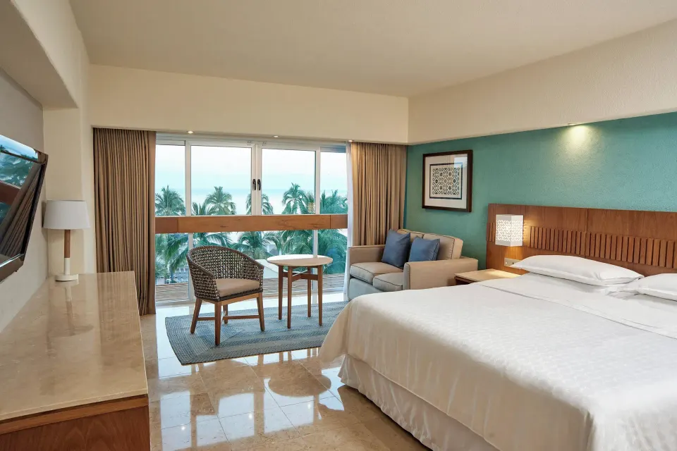 Deluxe Ocean View king room with sofa and palm views at Sheraton Buganvilias Puerto Vallarta.