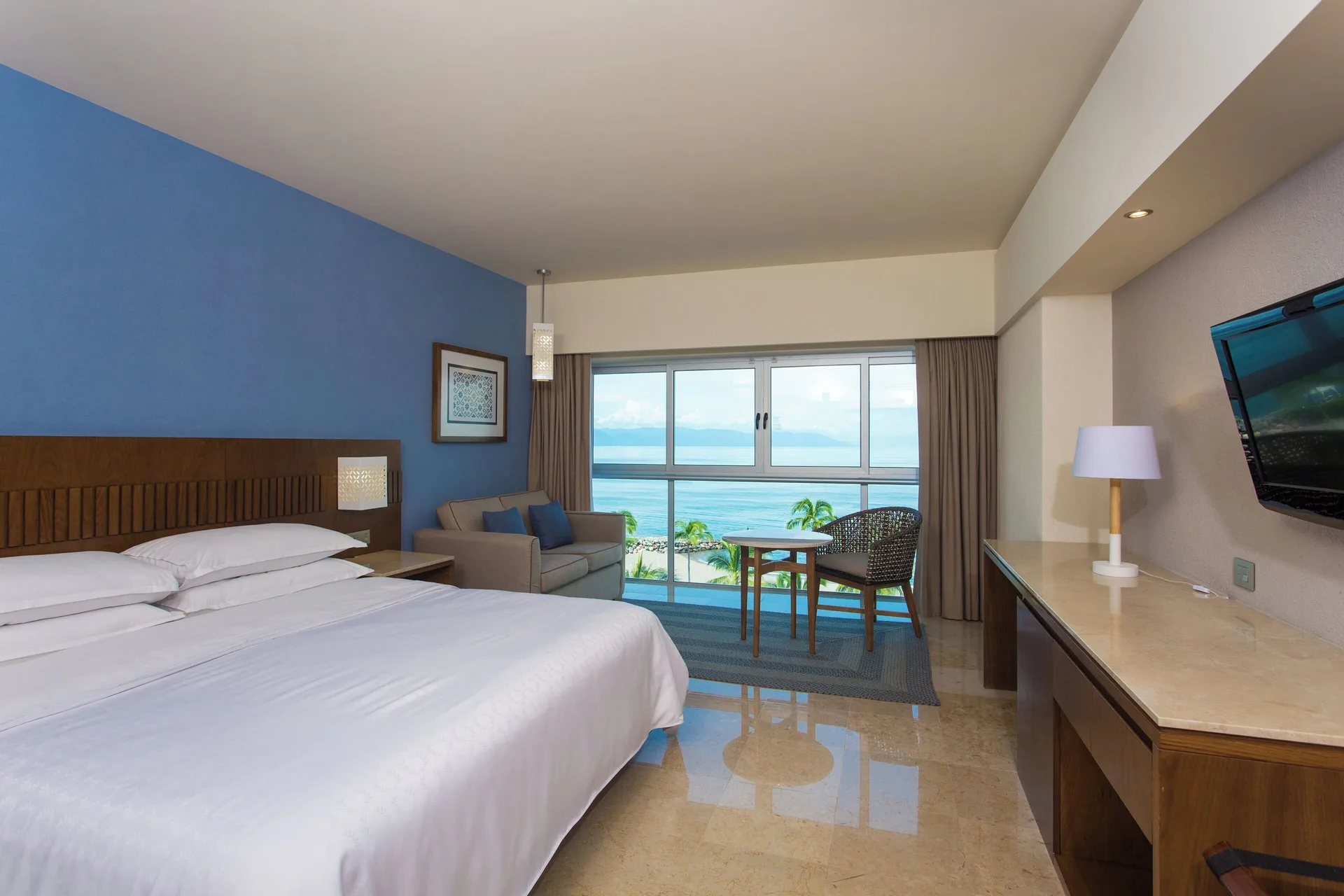 Deluxe Ocean View room with king bed and seating area at Sheraton Buganvilias Puerto Vallarta.