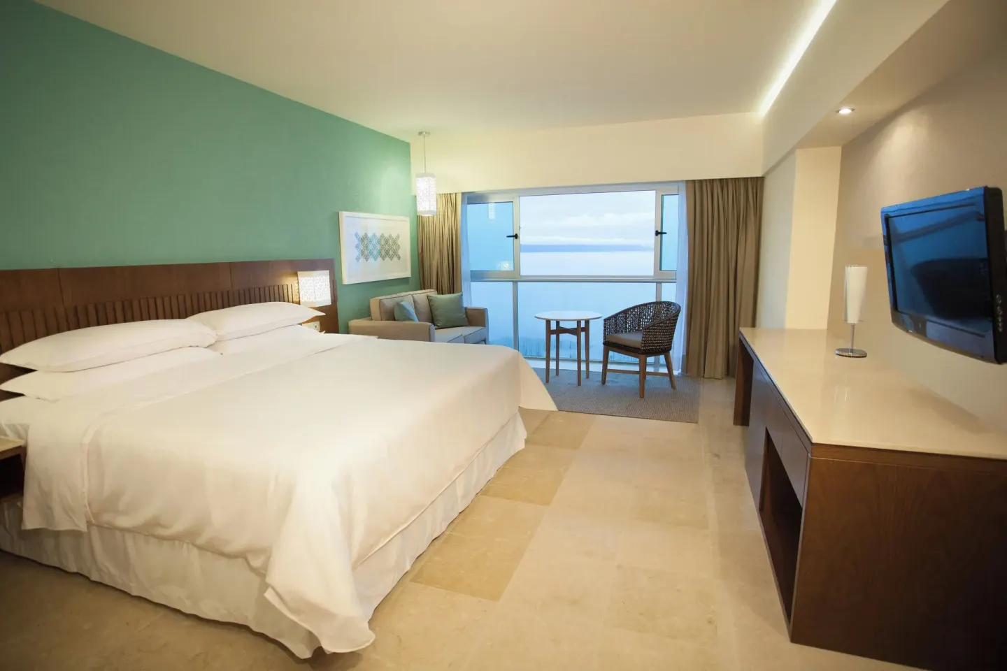 Deluxe Ocean View room with king bed and teal wall at Sheraton Buganvilias Puerto Vallarta.