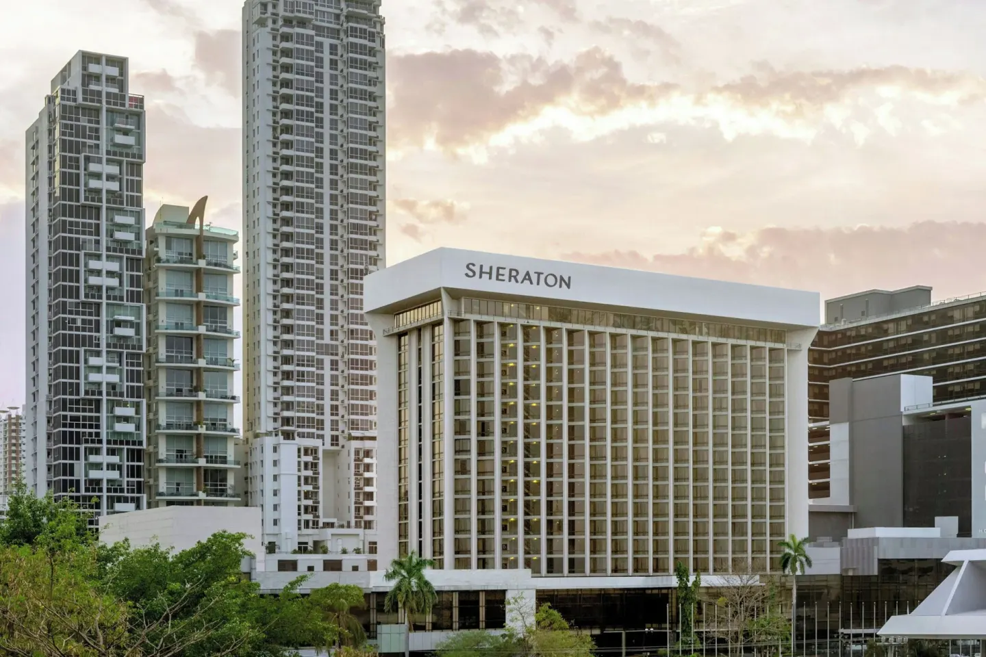Exterior tower of Sheraton Grand Panama rises among city high-rises at sunset.
