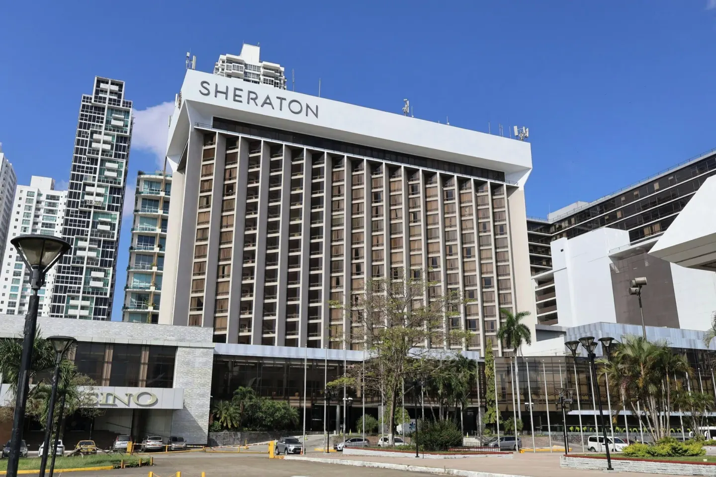 Street-level view of the Sheraton Grand Panama facade under a blue sky.