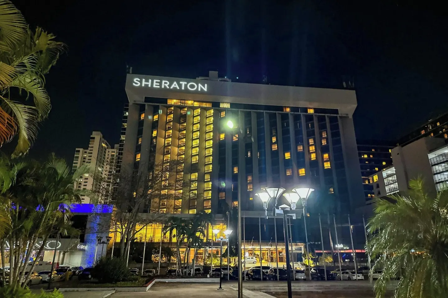 Sheraton Grand Panama exterior illuminated at night with palms in front.