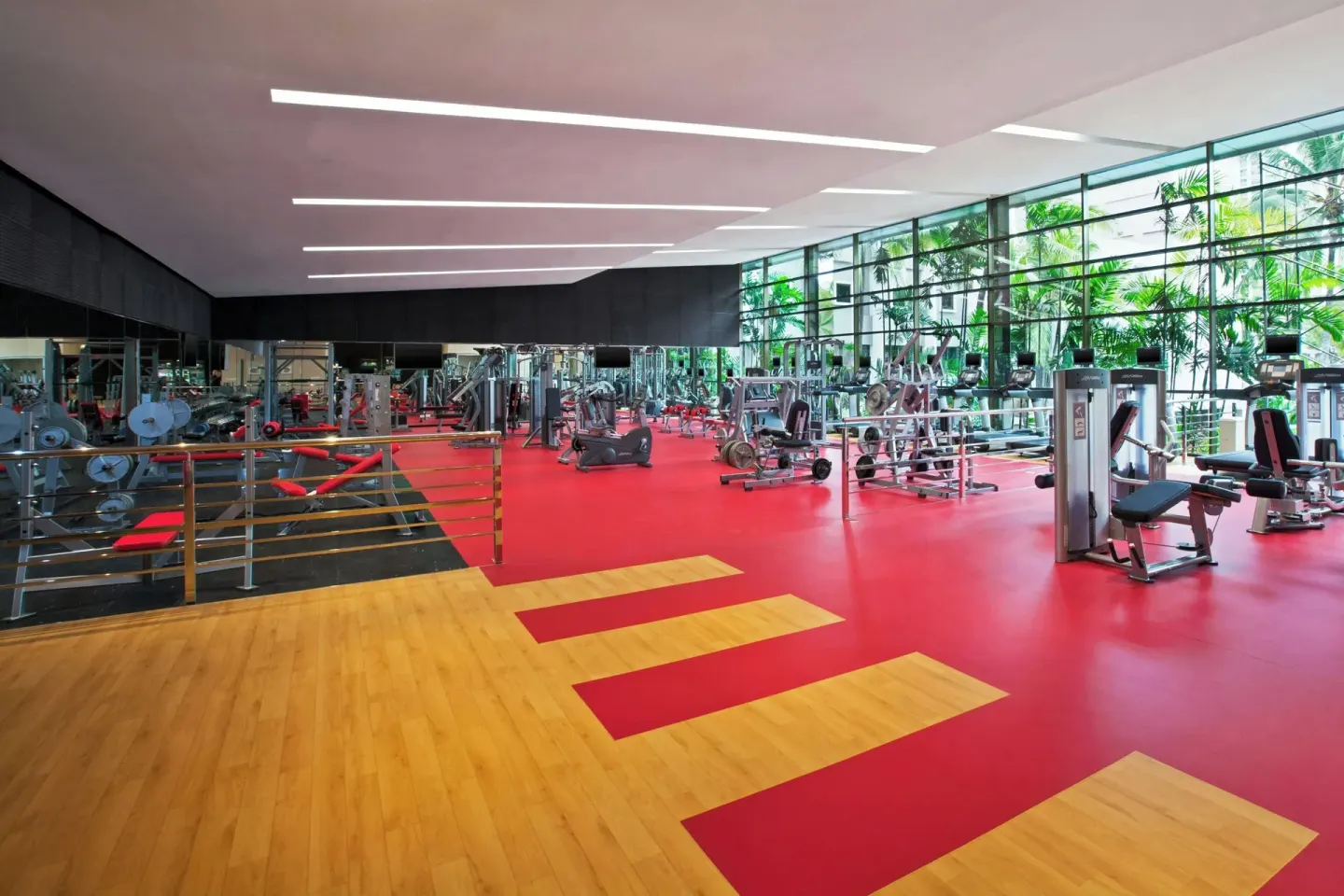 Large fitness center with red flooring and wood exercise area at Sheraton Grand Panama.