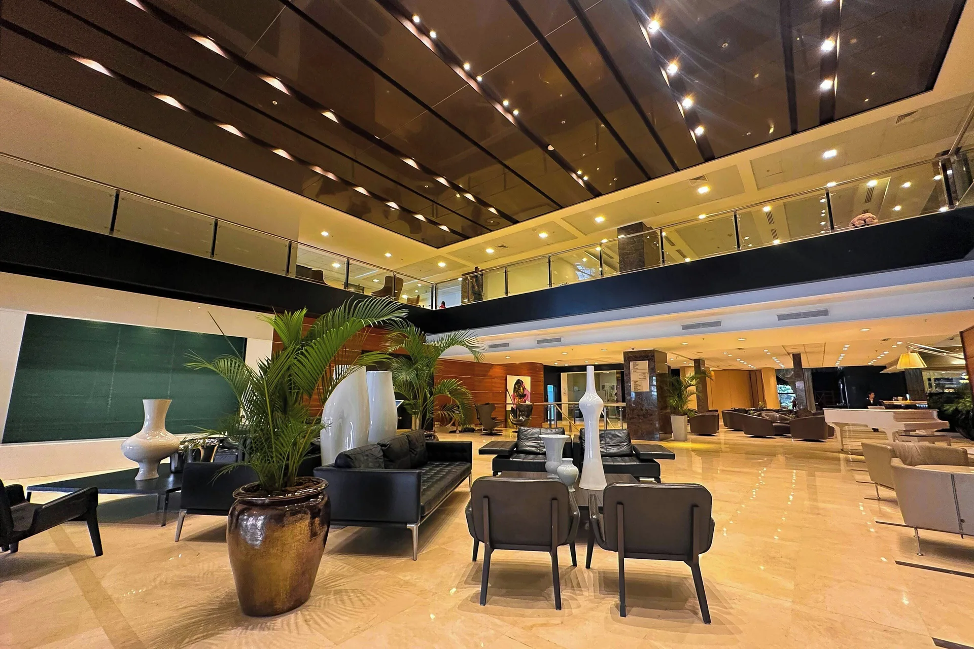 Lobby lounge with black sofas, plants, and upper balcony at Sheraton Grand Panama.