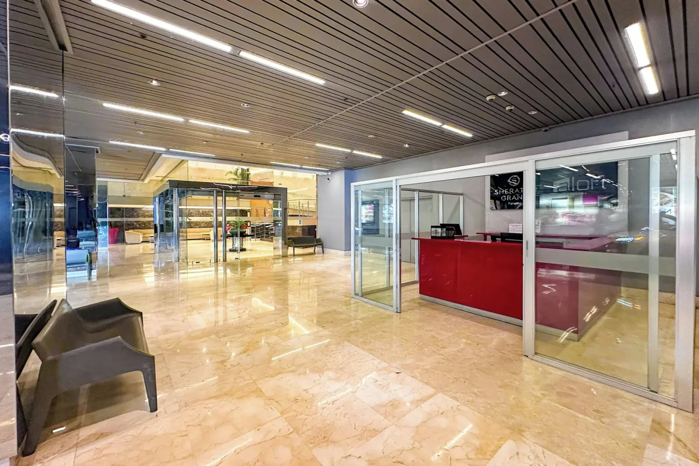 Marble lobby area with glass-walled desk and seating at Sheraton Grand Panama.