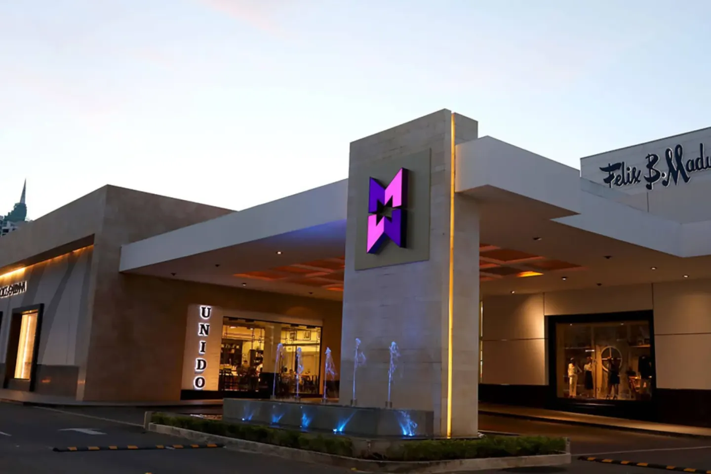 Illuminated shopping center entrance near Sheraton Grand Panama at dusk.