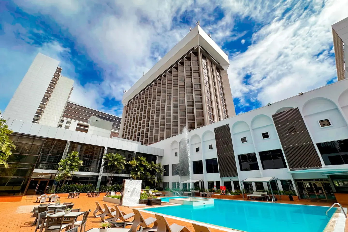 Outdoor pool and hotel towers at Sheraton Grand Panama under a bright sky.