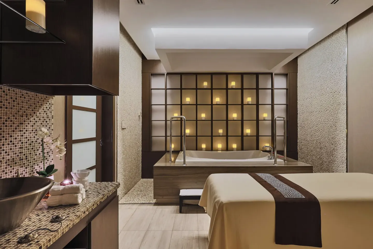 Massage bed facing a soaking tub and candle-lit wall at Sheraton Grand Panama.