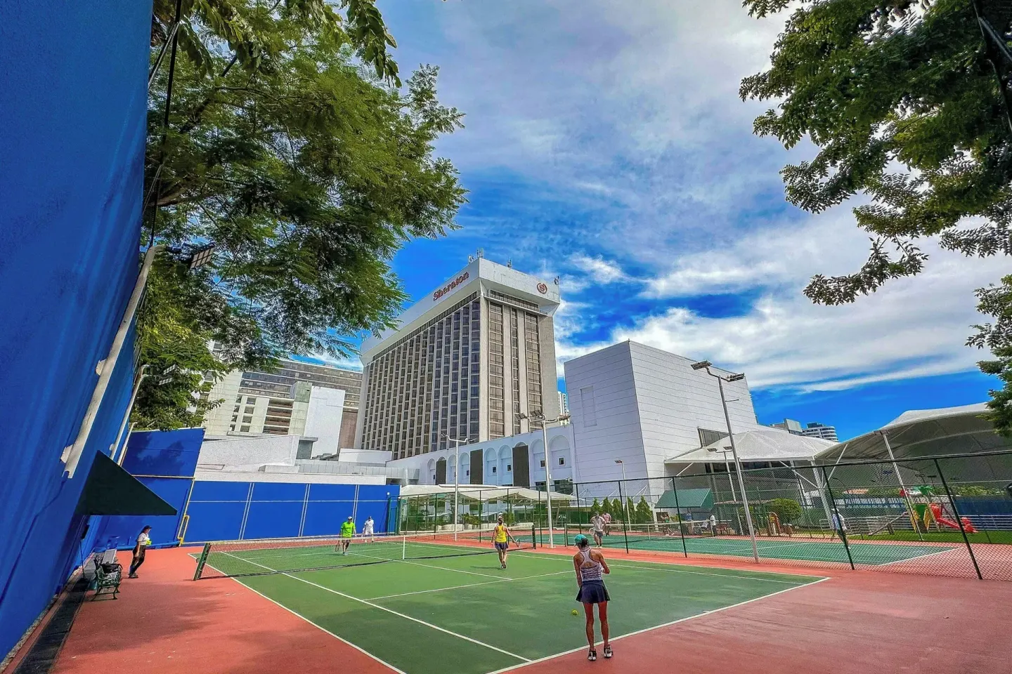 Tennis courts with players and the hotel tower at Sheraton Grand Panama.