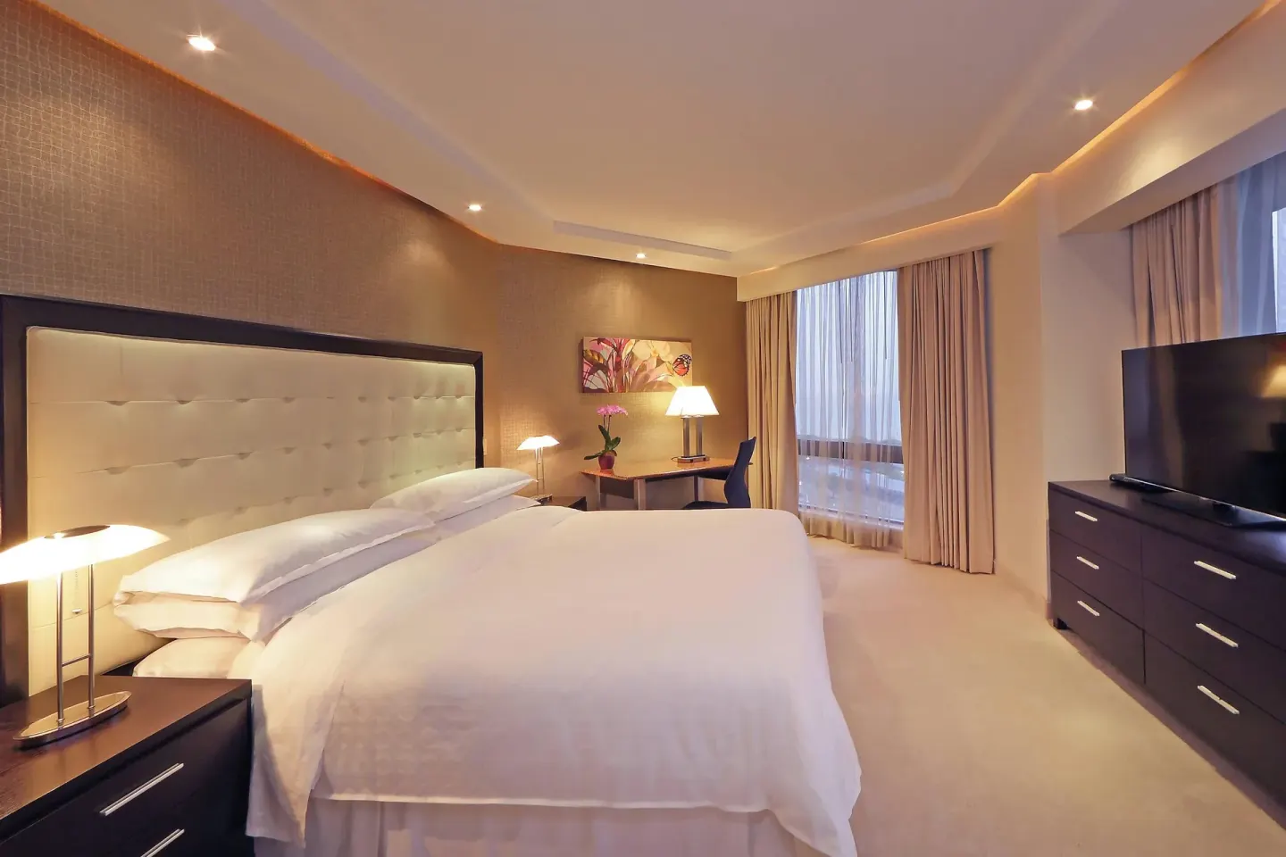 Club Room king bed with desk, TV and curtained windows at Sheraton Grand Panama.