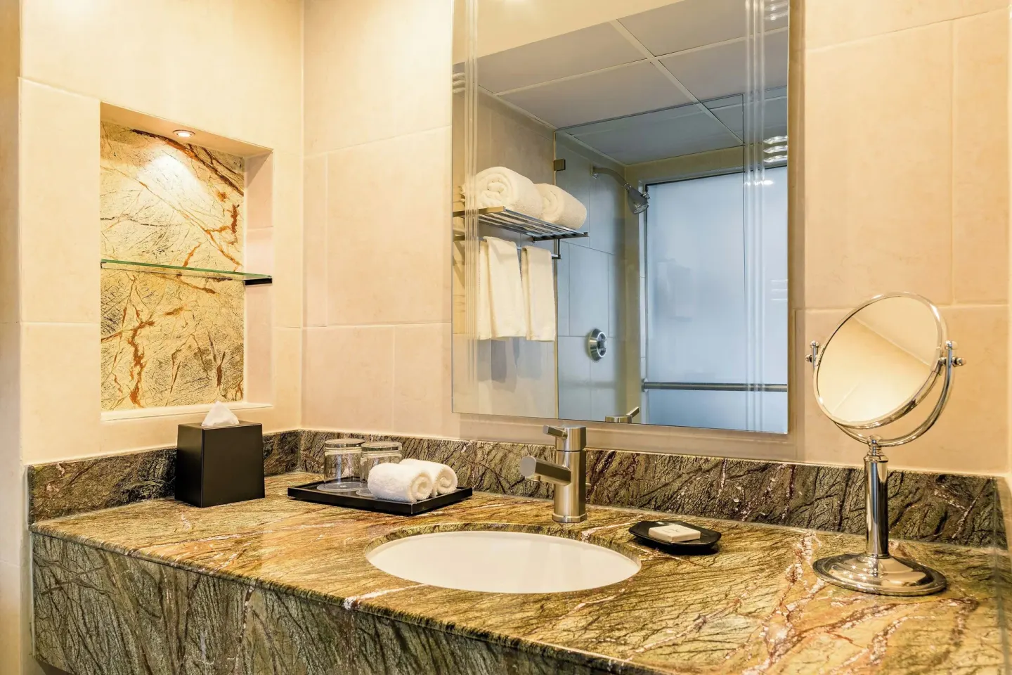 Deluxe Room bathroom vanity with sink, mirror, towels, and shower at Sheraton Grand Panama.