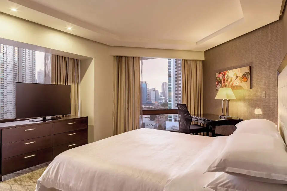 Deluxe Room with king bed, TV, desk, and city windows at Sheraton Grand Panama.