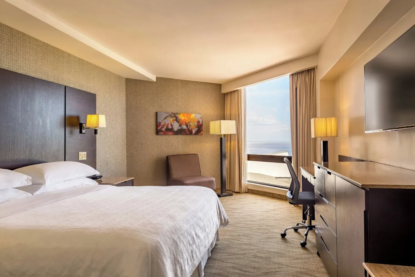 Deluxe Room with king bed, desk, chair, TV, and window view at Sheraton Grand Panama.